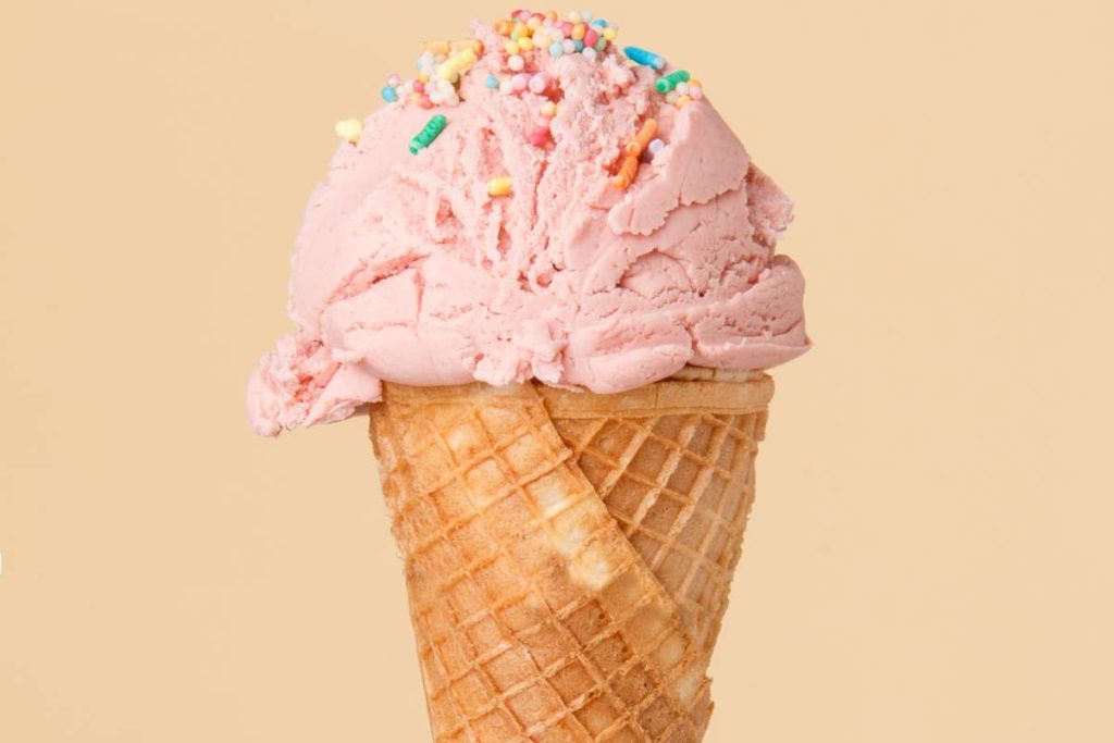 cornet-ice-cream-with-strawberry-scoop-colorful-surface