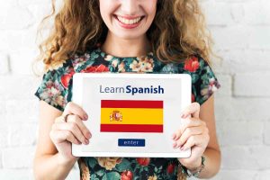 Girl holding a sign that says learn spanish