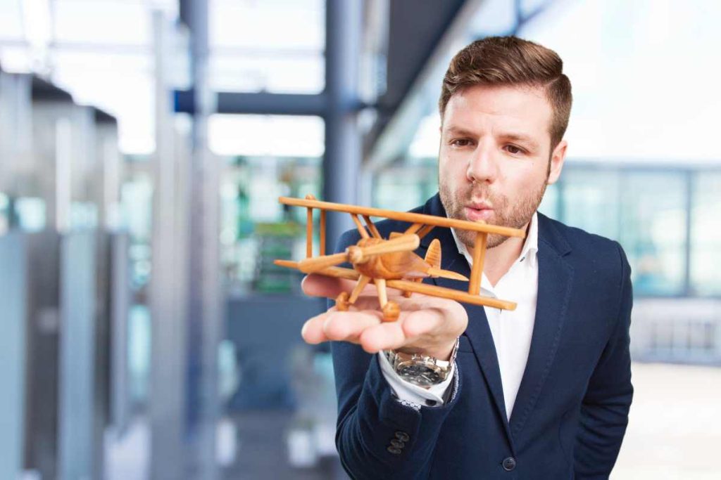 young business man holding a little wooden flight
